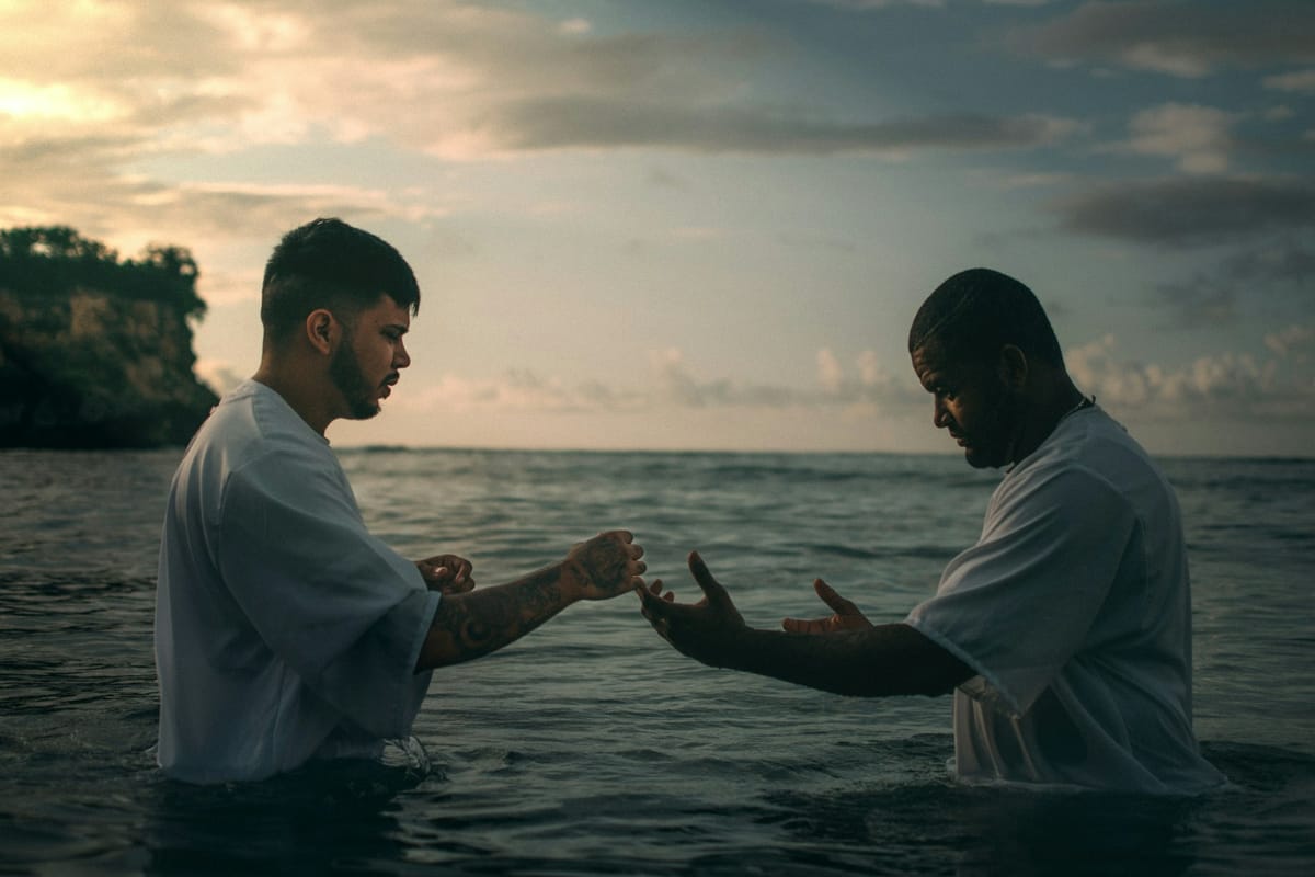 Two men in the water at a baptism at sunset